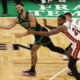 This action-packed image captures a dynamic moment during a basketball game, featuring a player from the Boston Celtics driving towards the basket with the ball, while defenders from the Miami Heat try to block his path. The Celtics player, wearing a green jersey with the number 0, exhibits skillful control and determination as he maneuvers around his opponents. The intense focus and physicality of the players are vividly displayed against the backdrop of the vibrant court, adding to the excitement of the match.