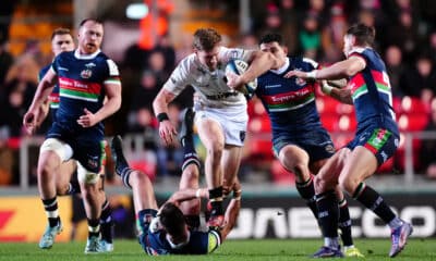 Intense rugby action with players from opposing teams tackling fiercely during a night game.